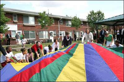 Mrs. Laura Bush joins the children and staff of the Meadowbrook Collaborative Community Center in playing with a colorful parachute during her visit to the facility Tuesday, June 6, 2006 in St. Louis Park, Minn.