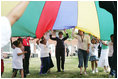 Mrs. Laura Bush participates in playing with a colorful parachute with children and staff outside the Meadowbrook Collaborative Community Center, Tuesday, June 6, 2006 in St. Louis Park. Minn.