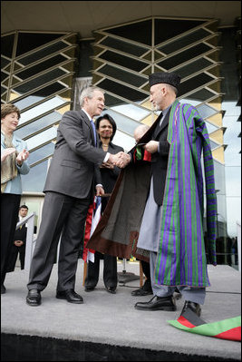 President George W. Bush and Afghanistan President Hamid Karzai shake hands after cutting the ceremonial ribbon, Wednesday, March 1, 2006, to dedicate the new U.S. Embassy Building in Kabul, Afghanistan. President Karzai thanked President Bush and the American people for their continued support to the Afghan people.