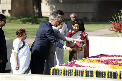 President George W. Bush and Laura Bush sprinkle flowers on the south side of the Mahatma Gandhi Memorial Thursday, March 2, 2006, during a wreath-laying ceremony in Rajghat, India.
