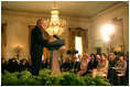 President George W. Bush joins in the celebration of International Women's Day at the White House Tuesday, March 7, 2006, as he thanks the female members of his audience for their leadership. "The struggle for women's right is a story of strong women willing to take the lead," the President told them and added, America's "a better place because of the leadership of women throughout our history."