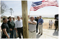 President George W. Bush watches as homeowner Jerry Akins places a flag outside his home Wednesday, March 8, 2006 in Gautier, Miss., on the site where the Akins family is rebuilding their home destroyed by Hurricane Katrina.