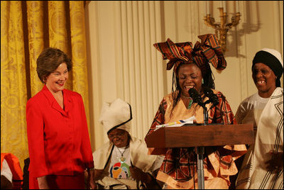 Mrs. Laura Bush reacts to remarks from Aunt Manyongo "Kunene" Mosima Tantoh, a member of the Mothers to Mothers-To-Be organization of South Africa, Monday, March 13, 2006 in the East Room at the White House. Mrs. Bush had earlier met with members of the group, who mentor and counsel mothers who come for prenatal care to clinics and find they are HIV-positive, on her visit to South Africa in July of 2005. Group member Gloria Ncanywa is seen at right.