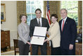President George W. Bush and Mrs. Bush present the Preserve America award for private preservation to Judy Christa-Cathey, Vice President Brand Management, and Scott Douglas Schrank, Vice President Brand Performance and Support, both of Hampton Hotels' nationwide Save-A-Landmark program, in the Oval Office Monday, May 1, 2006.