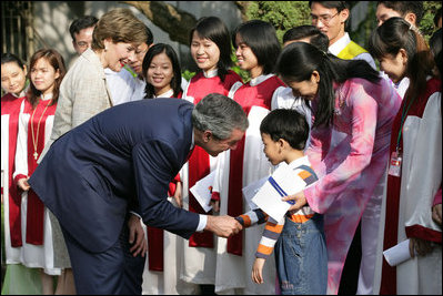 President George W. Bush and Mrs. Laura Bush pause to greet a young boy as they leave church services Sunday, Nov. 19, 2006, at the Cua Bac Church in Hanoi.