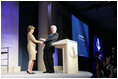 Mrs. Laura Bush is welcomed to the podium by former President Bill Clinton Wednesday, September 20, 2006, at President Clinton's Annual Global Initiative Conference in New York. During her remarks, Mrs. Bush announced a $60 million public-private partnership between the U.S. Government and the Case Foundation to provide clean water for up to 10 million people in sub-Sahara Africa by 2010. The partnership will support the provision and installation of PlayPump water systems in approximately 650 schools, health centers and HIV affected communities.
