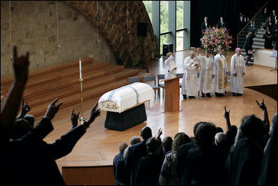 The 'Hooke' em horns' sign is given by mourners at the conclusion of the funeral service for former first lady Lady Bird Johnson Saturday, July 14, 2007, at the Riverbend Center in Austin, Texas.