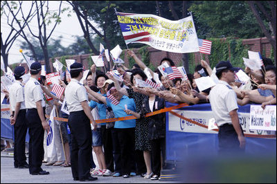 Crowds cheer and wave flags as the motorcade of President George W. Bush and Mrs. Laura Bush passes Tuesday, Aug. 5, 2008, following President Bush's arrival to Seoul, South Korea.