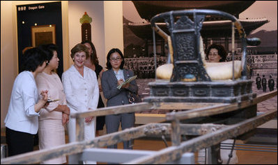 Mrs. Laura Bush gets a tour of the National Folk Museum of Korea in Seoul. Next to her in the light rose suit is Mrs. Kim Yoon-ok, wife of the President of the Republic of Korea.