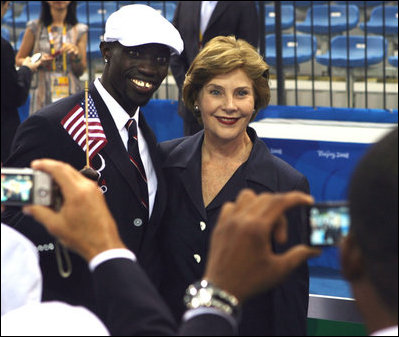 Mrs. Laura Bush with U.S. Flag Bearer Lopez Lomong as she greets members of the U.S. Summer Olympic Team at the Fencing Hall in Beijing on August 8, 2008. Mr. Lomong is a survivor of the violence in his native Sudan. He is now a U.S. citizen and was selected by his teammates to lead the U.S. Olympic team into the Olympic National Stadium carrying the United States Flag at the Opening Ceremony, which followed shortly after this picture was taken. 