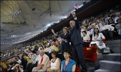 President George W. Bush waves an American flag as he and Mrs. Laura Bush stand and cheer during the entrance of the U.S. athletes into China's National Stadium Friday, Aug. 8, 2008, in Beijing.