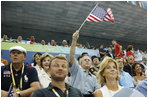 President George W. Bush, accompanied by Mrs. Laura Bush, waves an American flag as he cheers for the U.S. Olympic swimming team Monday, Aug. 11, 2008, in the National Aquatic Center at the 2008 Summer Olympic Games in Beijing.