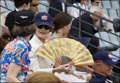 Mrs. Laura Bush wearing a U.S. Olympic baseball team hat uses a fan to keep cool as she watches the U.S. Olympic men's baseball team play a practice game against the Chinese Olympic men's baseball team Monday, Aug. 11, 2008, at the 2008 Summer Olympic Games in Beijing.
