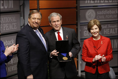 President George W. Bush, joined by Mrs. Laura Bush, is presented with the International Medal of PEACE by Pastor Rick Warren, Monday, Dec. 1, 2008, following their partipation at the Saddleback Civil Forum on Global Health in Washington, D.C.