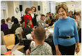 Mrs. Laura Bush greets one of the military volunteers and his child during the Saturday, Dec. 6, 2008, American Red Cross Holiday Mail for Heroes event in Washington, D.C. Standing in the background are American Red Cross President and CEO Gail McGovern, in red, and Bonnie McElveen-Hunter, Chairman of the American Red Cross. As the room full of volunteers sorted cards created by Americans to send to U.S. troops deployed around the world, Mrs. Bush encouraged Americans to do volunteer work in their home towns for those in need of food, care or appreciation. Cards for the troops can still be sent until December 10th at designated post office boxes.