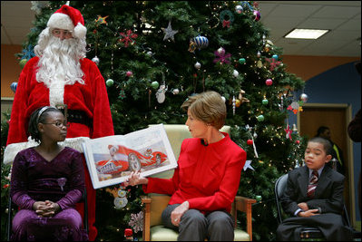Mrs. Laura Bush reads "My Penguin Osbert" Monday, Dec. 15, 2008 to a gathering of patients and their families at Children's National Medical Center in Washington, D.C. Sitting with her are patient escort volunteers Dania Jecty, left, age 11, and Elmer Reyes, age 13.