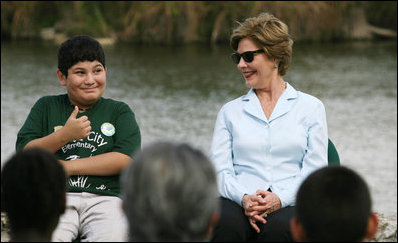 Mrs. Laura Bush smiles as a Florida City Elementary School student gives a thumbs-up while sitting on stage with Mrs. Bush, Wednesday, Feb. 6, 2008, during the Junior Ranger "First Bloom" planting event in Everglades National Park, Fla. Mrs. Bush praised the Everglades restoration program which will help bring back native trees in areas of the Everglades overgrown with non-native plants.