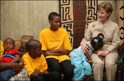 A young girl rests her head on Mrs. Laura Bush’s lap Sunday, Feb. 17, 2008, as she visits with orphans and caretakers in the Living Room of the WAMA Foundation, a non-profit organization founded by Salma Kikwete, First Lady of Tanzania.
