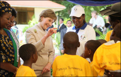 Mrs. Laura Bush waves to a child as she tours the stations of the WAMA Foundation in Dar es Salaam Sunday, Feb. 17, 2008. The Foundation is a non-profit founded by Mrs. Salma Kikwete, First Lady of Tanzania, focusing on development by improving women’s social and economic status by redefining gender roles and creating more opportunities for the development of women and children.