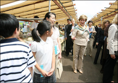 Mrs. Laura Bush waves at children as she walks the aisles of the Hokkaido Marche, a farmer's market in Makkari Village, on Hoikkaido, Japan, Tuesday, July 8, 2008, during a G-8 Spouses Program. Makkari, a village of 2,323 people, is known especially for its lilies and its potatoes.