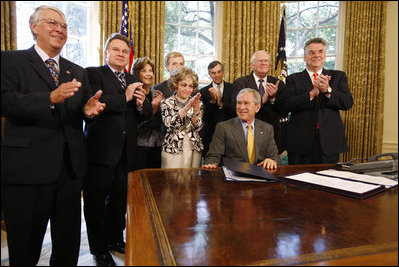 President George W. Bush is applauded after signing H.J. Res. 93, the Renewal of Import Restrictions on Burma and H.R. 3890, the Tom Lantos Block Burmese JADE Act of 2008, Tuesday, July 29, 2008 in the Oval Office of the White House. Applauding President Bush are, from left, Rep. Don Mansullo, R-Ill.; Rep. Chris Smith, R-N.J.; Mrs. Laura Bush, Annette Lantos, widow of Rep. Tom Lantos; Lantos grandson, Shiloh Tilleman; Rep.Rush Holt, D-N.J.; Rep. Joe Pitts, R-Pa.; and Rep. Peter King, R-N.Y.