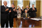 President George W. Bush is applauded after signing H.J. Res. 93, the Renewal of Import Restrictions on Burma and H.R. 3890, the Tom Lantos Block Burmese JADE Act of 2008, Tuesday, July 29, 2008 in the Oval Office of the White House. Applauding President Bush are, from left, Rep. Don Mansullo, R-Ill.; Rep. Chris Smith, R-N.J.; Mrs. Laura Bush, Annette Lantos, widow of Rep. Tom Lantos; Lantos grandson, Shiloh Tilleman; Rep.Rush Holt, D-N.J.; Rep. Joe Pitts, R-Pa.; and Rep. Peter King, R-N.Y.
