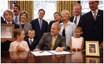 President George W. Bush is joined at his desk by Hannah Lewis, age 7, left, Wyatt Rech, age 6, Eden Adams, age 8, right, Mrs. Laura Bush, other family members, and Sen. Norm Coleman R-MN; Rep. Deborah Pryce R-OH; and Rep. Chris Van Hollen D-MD; Tuesday, July 29, 2008, after signing the Caroline Pryce Walker Conquer Childhood Cancer Act of 2008 in the Oval Office of the White House.