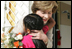 Mrs. Laura Bush hugs a young girl after she was presented with a bouquet of flowers upon her arrival welcome to the San Clemente Health Center Friday, Nov. 21, 2008, in San Clemente, Peru. Mrs. Bush visited the center and participated in interactive demonstrations depicting community-based health training.