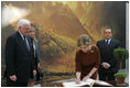 Mrs. Laura Bush signs the guest book Oct. 13, 2008 at the National Gallery of Art in Washington as Italian Prime Minister Silvio Berlusconi waits to sign as well. At left is Mr. Rusty Powell, Director of the National Gallery of Art, who led the tour. The Mt. Vesuvius mural is one of the backdrops for the exhibit.