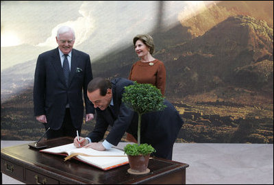 Italian Prime Minister Silvio Berlusconi follows Mrs. Laura Bush in signing the guest book Oct. 13, 2008 at the National Gallery of Art in Washington At left is Mr. Rusty Powell, Director of the National Gallery of Art, who led a tour of the exhibit "Pompeii and the Roman Villa; Art and Culture Around the Bay of Naples." The Mt. Vesuvius mural one of the backdrops for the exhibit.