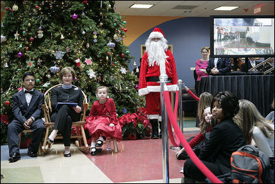 Mrs. Laura bush sits with patient escorts Issac Santana (age 12) and Amanda Merrell (age 5) along with Santa Claus (played by volunteer Jason Woods), while visting The Children's National Medical Center in Washington, D.C. and debuted "Barney Cam 2007: Holiday in National Parks."