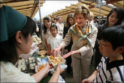 Mrs. Laura Bush samples the food at the Hokkaido Marche farmer's market in Makkari Village Tuesday, July 8, 2008, as part of the G8 spouses program. The small village on the northern Japanese island of Hokkaido is known for its lilies and its potatoes, and the market, organized especially for the occasion of the G8 Summit, showcased locally grown produce.