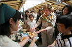 Mrs. Laura Bush samples the food at the Hokkaido Marche farmer's market in Makkari Village Tuesday, July 8, 2008, as part of the G8 spouses program. The small village on the northern Japanese island of Hokkaido is known for its lilies and its potatoes, and the market, organized especially for the occasion of the G8 Summit, showcased locally grown produce.