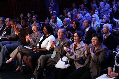 Mrs. Laura Bush applauds while listening to a panel discussion, flanked by NBA player Greg Oden, left, and student, Shantel Monk. Also seated with Mrs. Bush, at right, are Oregon Governor Theodore (Ted) Kulongoski and his, wife, Mrs. Mary Oberst.