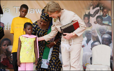 Mrs. Laura Bush pats the back of 7-year-old Zuwena Dooto, after she presented Mrs. Bush with a scrapbook during the launch of the National Plan for Action event at the WAMA Foundation Sunday, Feb. 17, 2008, in Dar es Salaam.