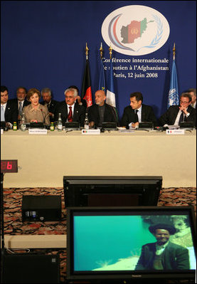 Mrs. Laura Bush offers remarks at the U.S.-Afghan Donor's Conference as visuals of one of her trips play on monitors in the center of the room for representatives from around the world to view. Seated next to her, from left, are Afghan Foreign Minister Dr. Ragin Dadfar Spanta, Afghan President Hamid Karzai, and French President Nicholas Sarkozy. The June 12, 2008 Paris meeting was at the Center de Conferences Internationals.