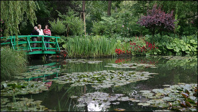 Mrs. Laura Bush tours the home and gardens of painter Claude Monet in Giverny, France. Mrs. Bush is accompanied by Mrs. Debbie Stapleton, in the red scarf, wife of the U.S. Ambassador to France Craig Roberts Stapleton, as she views Monet's inspiration for his water lilies paintings. Ms. Claire Toulgouat, left, leads the tour.