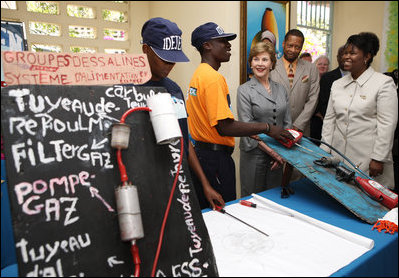 Mrs. Laura Bush, joined by Guerda Previlon, right, chief of party IDEJEN, and Gabriel Bienime, Haiti Education Minister, visits with a student enrolled in the IDEJEN educational program at the College de St. Martin Tours Thursday, March 13, 2008, in Port-au-Prince, Haiti.