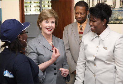 Mrs. Laura Bush, joined by Guerda Previlon, right, chief of party IDEJEN, and Gabriel Bienime, Haiti Education Minister, visits with a student enrolled in the IDEJEN educational program at the College de St. Martin Tours Thursday, March 13, 2008, in Port-au-Prince, Haiti. Mrs. Bush told students and teachers that it is "really important for students to realize they need to keep going, to study more, and really to complete school."