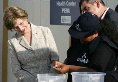 Mrs. Laura Bush looks on Friday, Nov. 21, 2008, as Ms. Maria Salguero Trillo, Community Health Educator Volunteer at the San Clemente Health Center in San Clemente, Peru, demonstrates how families are trained to treat contaminated water for safe drinking. In the town of 25,000, nearly 89 percent of the homes were affected by the August 2007, 8.0-magnitude earthquake.