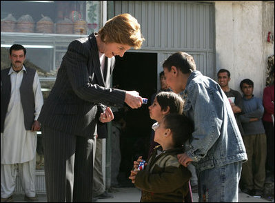 Laura Bush hands red, white and blue kaleidoscopes to youngsters outside a Kabul bakery Wednesday, March 30, 2005 during her visit to Afghanistan. 