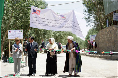 Mrs. Laura Bush, left, assists local officials with the ribbon cutting ceremony June 8, 2008 in Afghanistan at the ground-breaking ceremonies for the 1.96 kilometer Bamiyan road project through the bazaar. The new road will link up with a 1.72 kilometer road from the airport to the town center completed in 2007 with U.S. support.