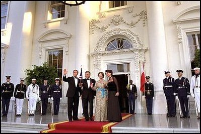 Flanked by some of America's finest servicemen, President Bush and Mrs. Bush wave to photographers with President Kwasniewski and Mrs. Kwasniewska as they welcome Poland's first couple to the State Dinner July 17. 
