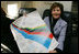Mrs. Laura Bush shows her signatured 2006 Winter Olympic poster during her flight home from Italy, Feb. 12, 2006.