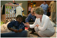 Laura Bush visits with a young boy displaced by Hurricane Katrina in the Cajundome at the University of Louisiana in Lafayette, La., Friday, Sept. 2, 2005.