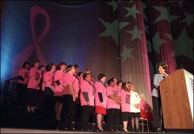 Laura Bush turns to acknowledge breast cancer survivors who share the stage with her at the "Embrace the Race" Susan G. Komen Breast Cancer Foundation dinner at the Mellon Auditorium in Washington, D.C., Thursday, March 6 , 2003. "Each of you show the world that a little hope, a lot of love, and abounding courage will pick us up every time," Mrs. Bush said. White House photo by Susan Sterner.