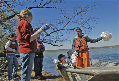 White House Intern Dee Moore tosses a bag of collected trash to Chad Pregracke, founder of Living Lands and Waters. As part of a service project, White House Interns spent several hours cleaning the banks of the Potomac River Thursday, April 13, 2005.