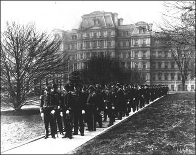 Admiral Dewey (front left) and Navy officers on their way from the Department of the Navy (background) to the White House to call upon the President on January 1, 1905.