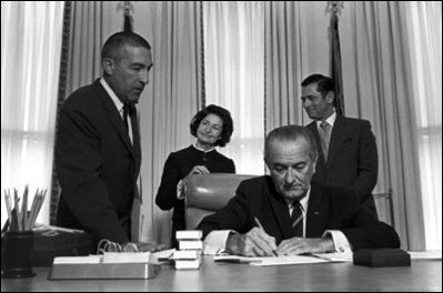 Former First Lady Lady Bird Johnson, center-background, watches as President Lyndon B. Johnson signs the Interior Department Appropriation Bill in the Oval Office Sept. 26, 1968. LBJ Library Photo by Yoichi Okamoto 