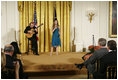 President George W. Bush, seated right-front, listens to the performance of singer Ana Cristina and guitarist Marco Linares, Friday, Oct. 6, 2006, in the East Room of the White House, in celebration of National Hispanic Heritage Month.